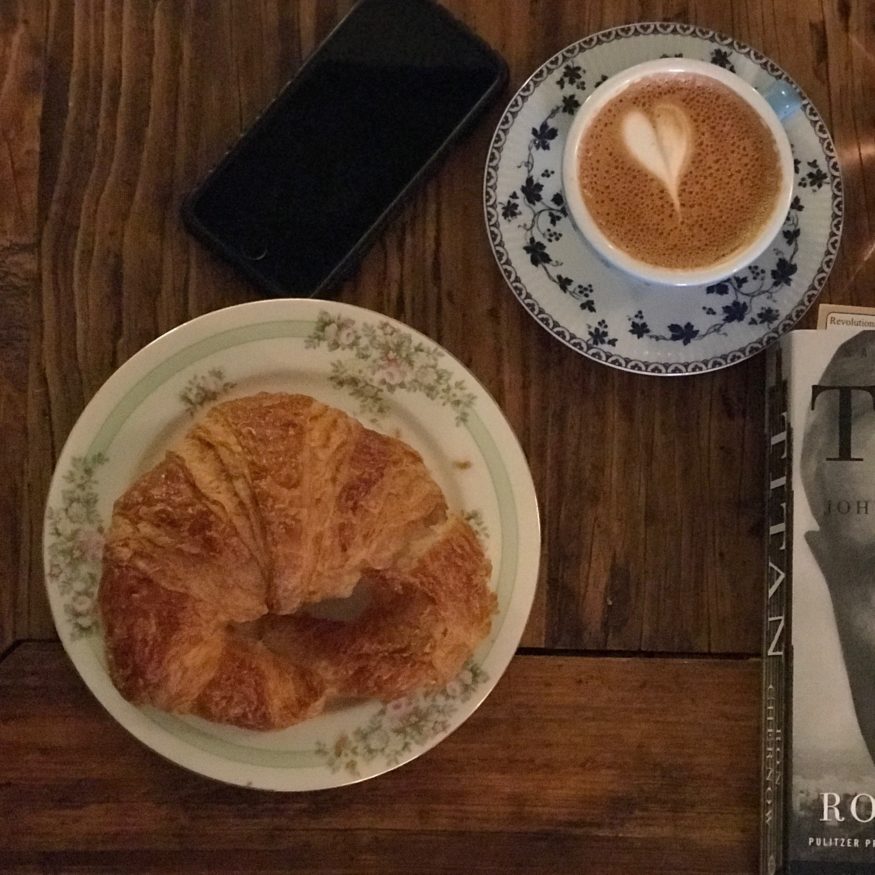 Croissant, cappuccino, and book ready for Series 7 license prep
